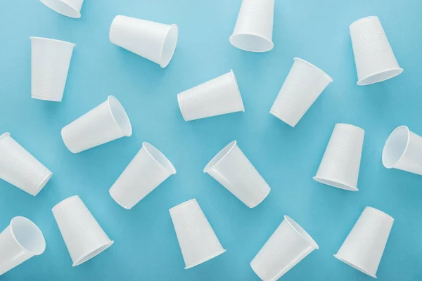 Vue de dessus des tasses blanches et en plastique sur fond bleu — Photo de stock