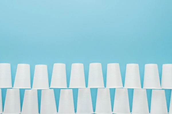 Couché plat avec des tasses en plastique blanc isolé sur bleu avec espace de copie — Photo de stock