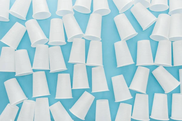 Vista dall'alto di tazze bianche e di plastica su sfondo blu — Foto stock