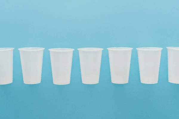 Flat lay with white plastic cups isolated on blue with copy space — Stock Photo