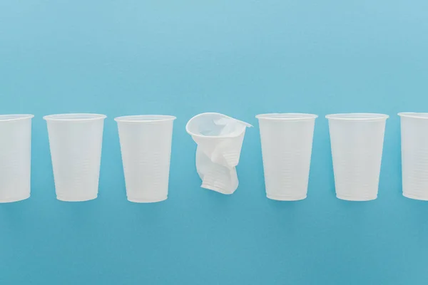 Flat lay with white plastic cups on blue background with copy space — Stock Photo