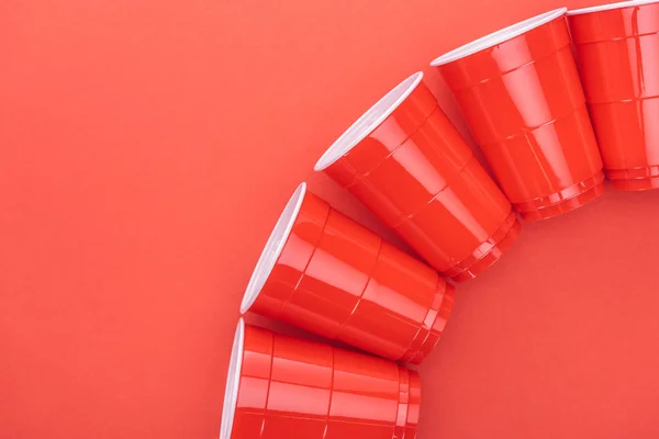 Flache Lage mit hellen und bunten Plastikbechern isoliert auf rotem Hexenkopierraum — Stockfoto