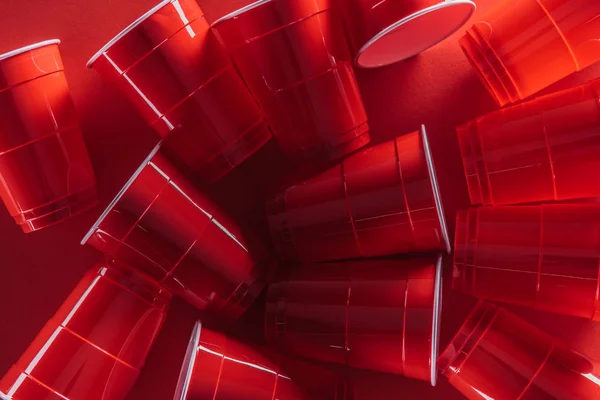 Vue de dessus de gobelets en plastique lumineux et coloré sur fond rouge — Photo de stock