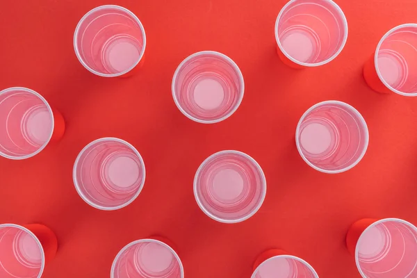 Vue de dessus de gobelets en plastique lumineux et coloré sur fond rouge — Photo de stock