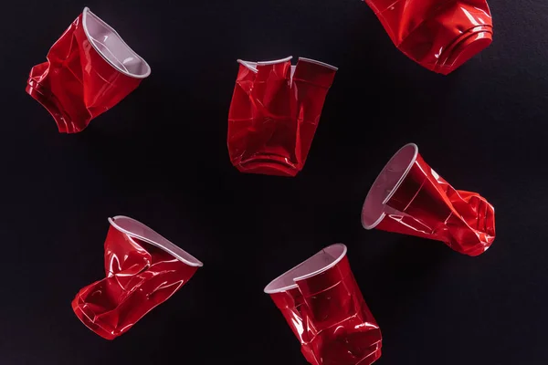 Vue de dessus de lumineux et coloré, gobelets en plastique rouge isolé sur noir — Photo de stock