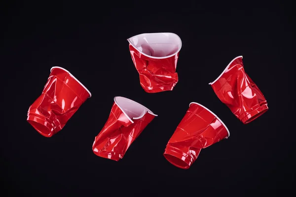 Vue de dessus de lumineux et coloré, gobelets en plastique rouge isolé sur noir avec espace de copie — Photo de stock