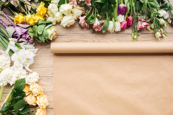 Vista superior de papel artesanal y flores frescas en la superficie de madera - foto de stock