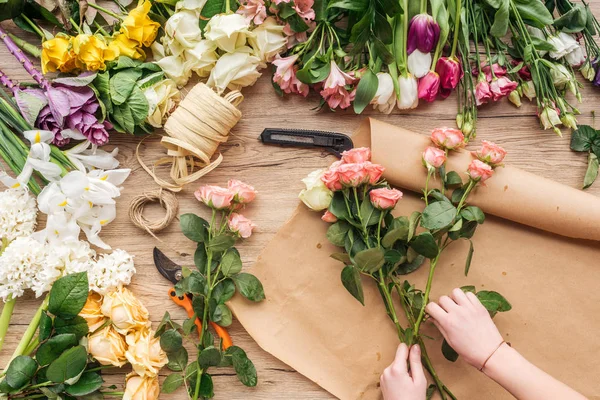 Vista parcial do florista fazendo buquê de flores na superfície de madeira — Fotografia de Stock