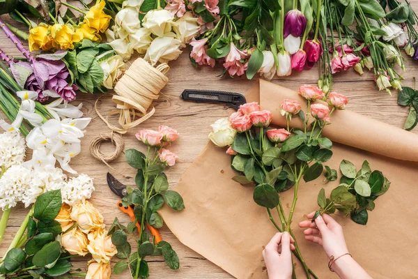 Vista parcial do florista fazendo buquê de flores na superfície de madeira — Fotografia de Stock