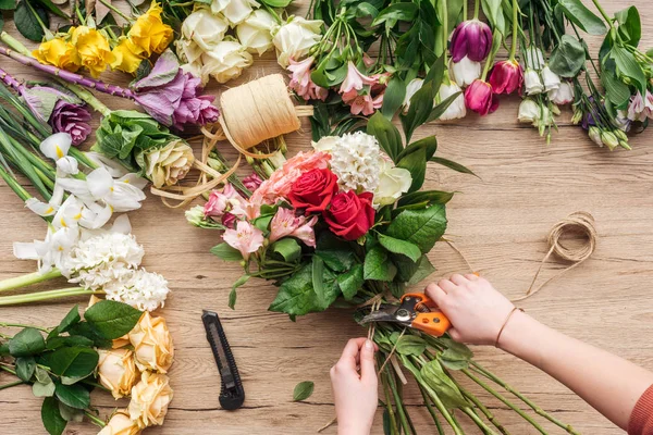 Vista cortada de florista fazendo buquê de flores na superfície de madeira — Fotografia de Stock