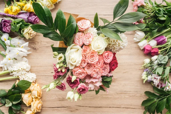 Draufsicht auf bunten Blumenstrauß mit grünen Blättern auf Holzoberfläche — Stockfoto