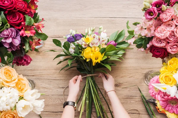 Zugeschnittene Ansicht des Floristen, der Blumenstrauß auf Holzoberfläche herstellt — Stockfoto