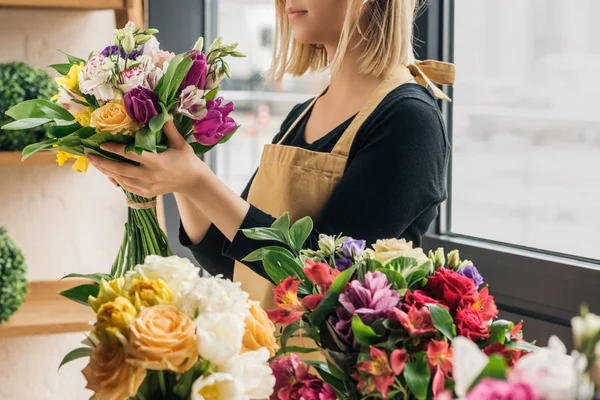 Vista recortada de floristería en delantal que sostiene el ramo en la tienda de flores - foto de stock