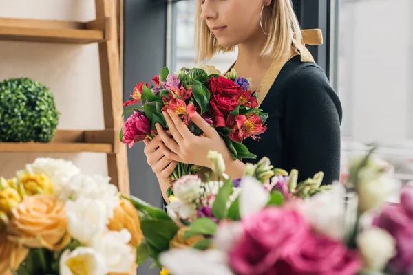 Cropped view of florist in apron holding bouquet in flower shop — Stock Photo