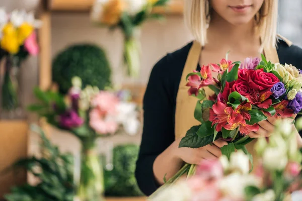 Vue recadrée du fleuriste en tablier tenant bouquet dans la boutique de fleurs — Photo de stock