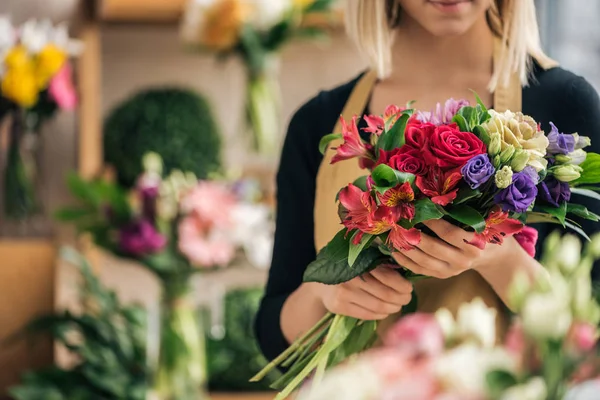 Vista cortada de florista em avental segurando buquê na loja de flores — Fotografia de Stock