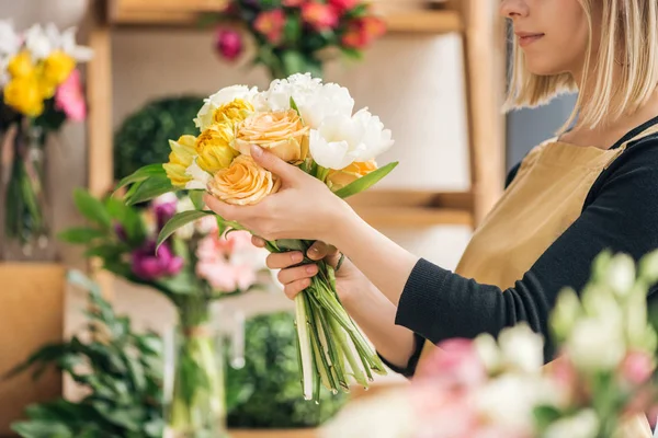 Vue recadrée du fleuriste en tablier tenant bouquet dans la boutique de fleurs — Photo de stock