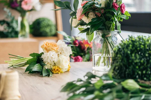 Bouquets de fleurs fraîches sur table en bois dans la boutique de fleurs — Photo de stock