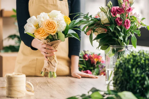 Cropped view of florist in apron holding flower bouquet — Stock Photo