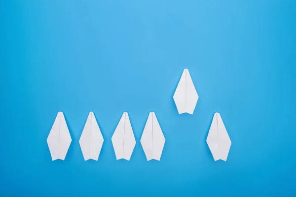 Flat lay with white paper planes on blue surface — Stock Photo