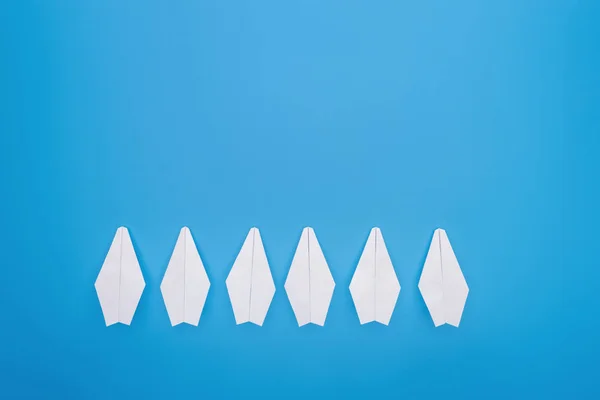 Flat lay with white paper planes on blue surface — Stock Photo
