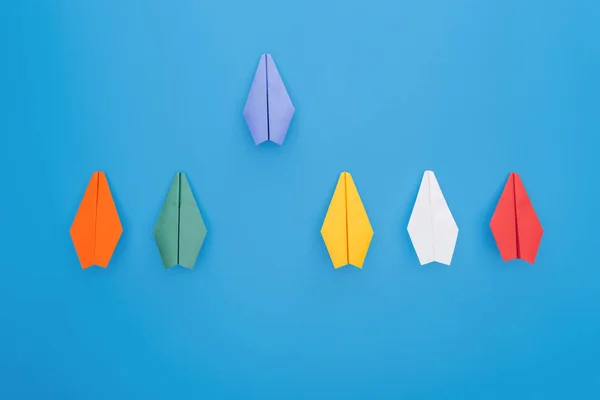 Flat lay with colorful paper planes on blue surface — Stock Photo