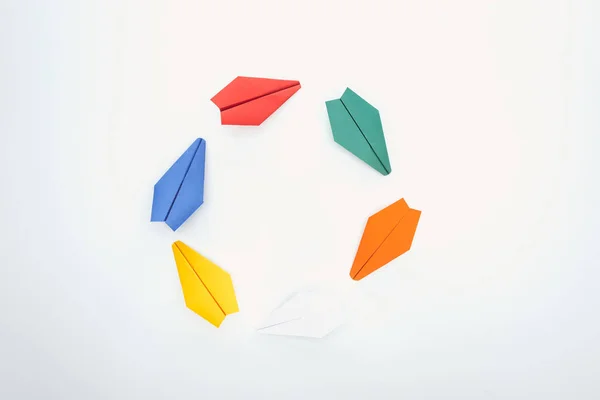 Flat lay with colorful paper planes on white surface — Stock Photo