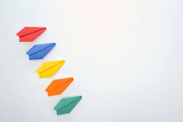 Flat lay with colorful paper planes on white surface — Stock Photo