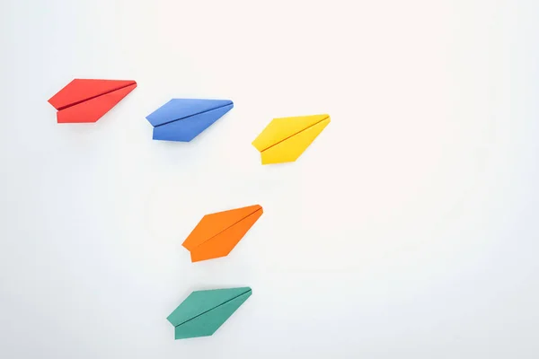 Flat lay with colorful paper planes on white surface — Stock Photo