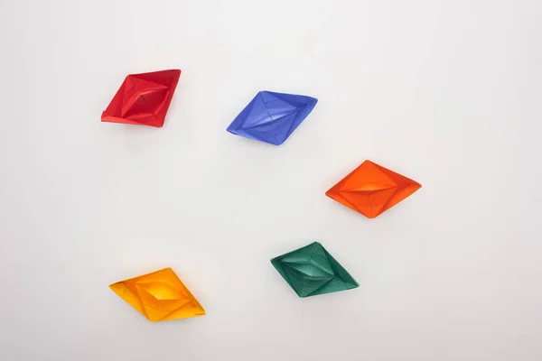 Top view of colorful paper boats on white surface — Stock Photo