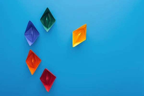 Top view of colorful paper boats on blue surface — Stock Photo