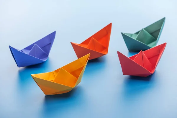 Цветные яркие бумажные лодки на светло-голубой поверхности — стоковое фото