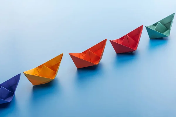 Bateaux en papier lumineux coloré sur la surface bleu clair — Photo de stock