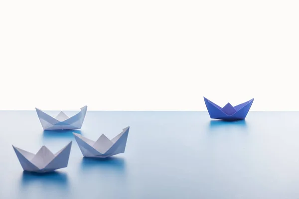 Barcos de papel na superfície azul clara no fundo branco — Fotografia de Stock