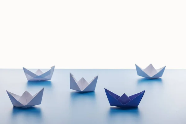 Paper boats on light blue surface on white background — Stock Photo