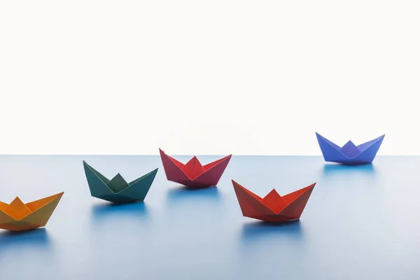 Colorful paper boats on light surface on white background — Stock Photo