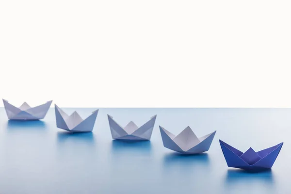 Barcos de papel na superfície azul clara no fundo branco — Fotografia de Stock