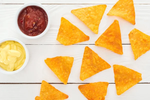 Top view of tasty nachos and sauces on white wooden table — Stock Photo