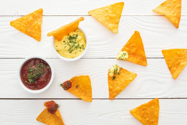 Vista superior de nachos saborosos e molhos na superfície branca e de madeira — Fotografia de Stock