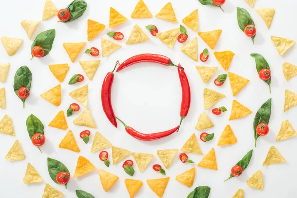 Vue de dessus des nachos savoureux et des piments tranchés avec des feuilles de basilic et des tomates cerises — Photo de stock