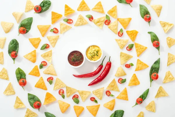 Vista dall'alto di gustosi nachos, salse e peperoncini tagliati a fette con basilico e pomodorini — Foto stock