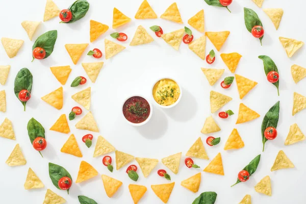 Top view of tasty nachos, sauces and sliced chili peppers with basil and cherry tomatoes — Stock Photo