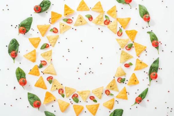 Vista superior de nachos saborosos, especiarias e pimentas fatiadas com manjericão e tomates cereja maduros — Fotografia de Stock