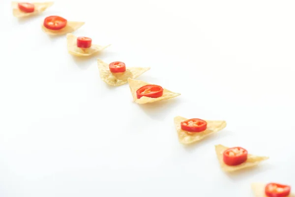 Flat lay with tasty nachos and sliced chili peppers on white background with copy space — Stock Photo
