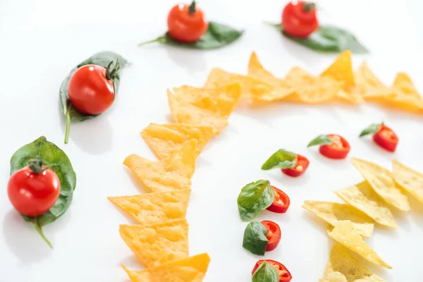 Foco seletivo de nachos saborosos, tomates cereja e pimentas com manjericão — Fotografia de Stock