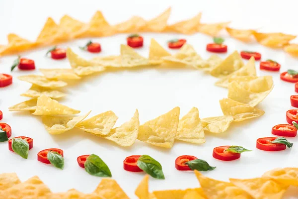 Foco seletivo de nachos saborosos e pimentas com manjericão sobre fundo branco — Fotografia de Stock