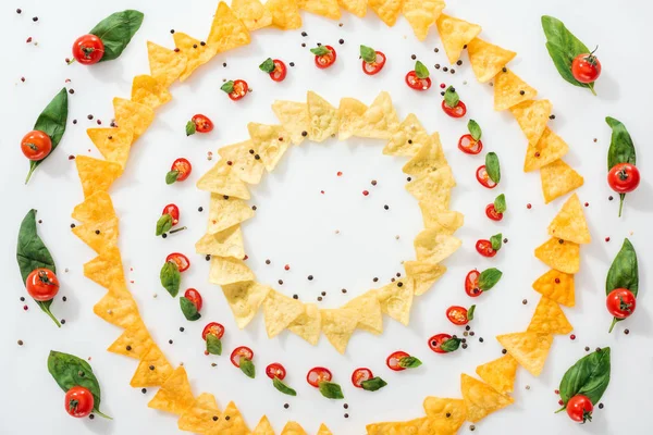 Blick von oben auf leckere Nachos, Gewürze und geschnittene Chilischoten mit Basilikum und reifen Kirschtomaten — Stockfoto