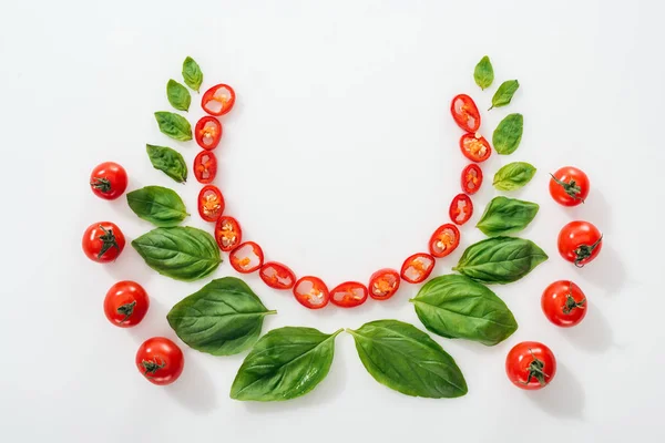 Flat lay with cut chili peppers, basil leaves and ripe cherry tomatoes on white background with copy space — Stock Photo