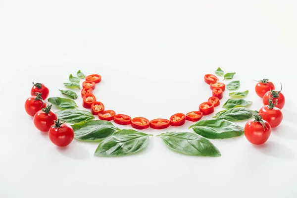 Flache Lage mit geschnittenen Chilischoten, Basilikumblättern und reifen Kirschtomaten auf weißem Hintergrund — Stockfoto