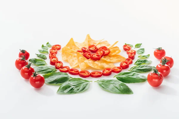 Leigos planos com nachos, pimentas cortadas, folhas de manjericão e tomates cereja maduros sobre fundo branco — Fotografia de Stock